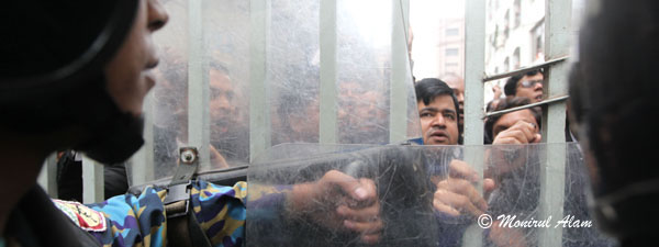 DEC 11 2012-Dhak, Bangladesh- Bangladeshi police stand guard and BNP lawyers shout slogan in form of CMM court during the Hortal hour.BNP and its close ally Jamaat-e-Islami observed dawn-to-dusk nationwide strike on Tuesday. They are demanding restoration of the caretaker government system. © Monirul Alam